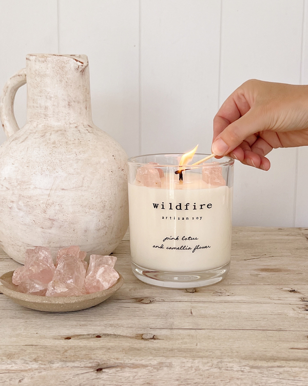 Wildfire soy candle limited edition with rose quartz. Wick being lit with a match. Soft pink and cream aesthetic